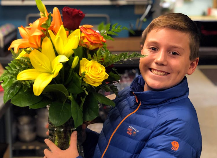 A young member of the Welke family holds a beautiful bouquet of red, yellow and orange roses